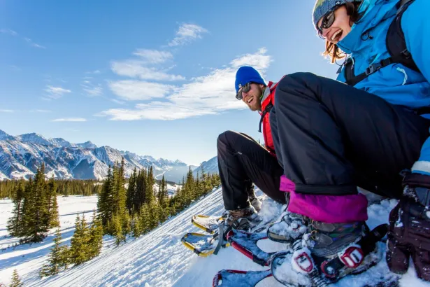 Two happy snowshoers sitting on snowy hill at Fortress Mountain
