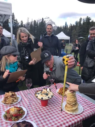 Judges measuring height of pancake stack at Backcountry Iron Chef teambuilding activity, Banff and Canmore Canadian Rockies