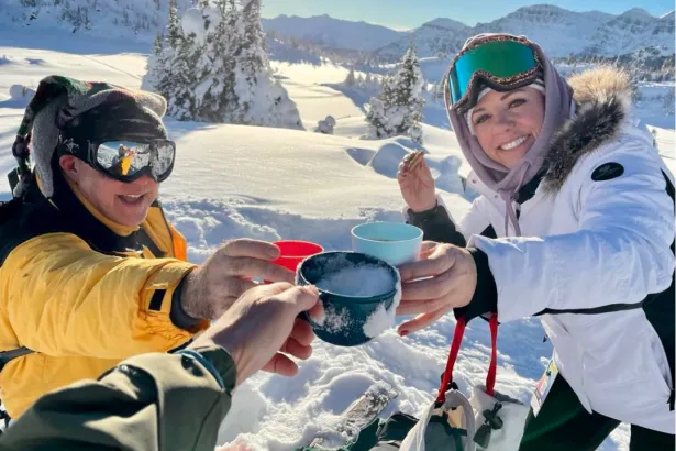 First-person view of a snowshoeing group cheersing mugs of hot chocolate in the Canadian Rockies
