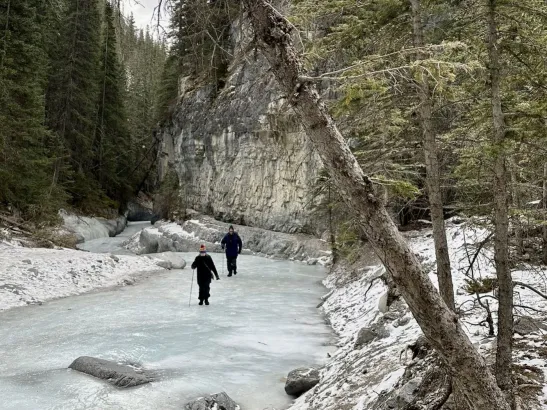 People walking on frozen river of clear ice in Grotto Canyon