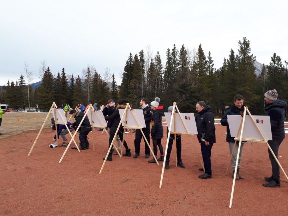 Group standing in front of painting easels in mountain setting