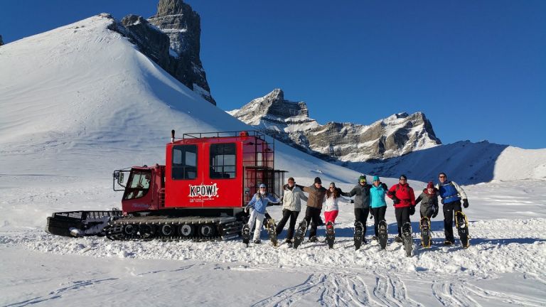 Snowshoeing Group posing in front of snowcat in winter